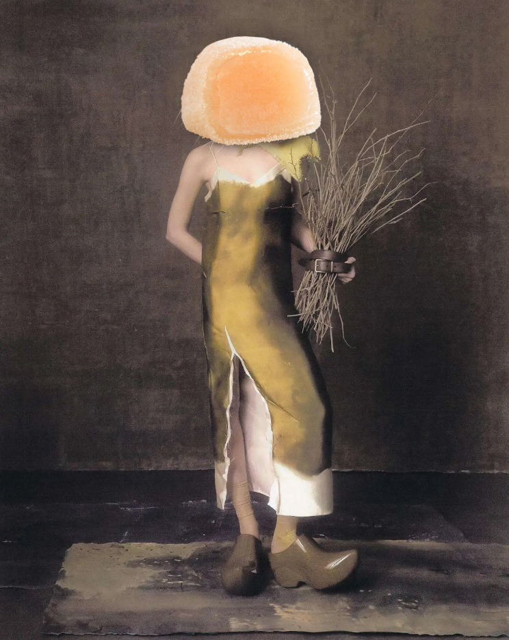 women in green dress and matching clogs holding sticks bundled by belt